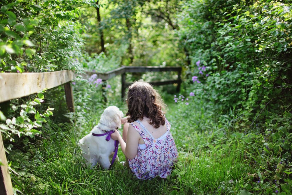 Girl sitting in field with puppy